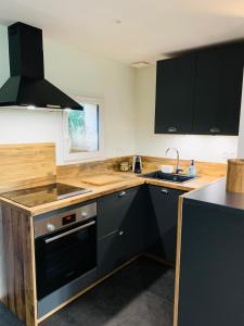 een keuken met zwarte kasten en een wastafel bij Cottage in Missillac