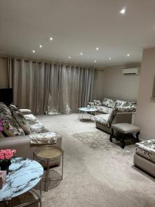 a large living room with couches and tables in it at Amazing 4 Bedrooms family home with free parking in Romford