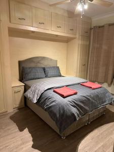 a bedroom with a bed with two red towels on it at Amazing 4 Bedrooms family home with free parking in Romford