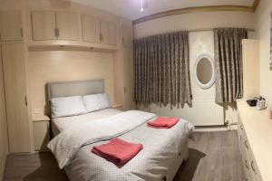 - une chambre avec un lit et 2 serviettes rouges dans l'établissement Amazing 4 Bedrooms family home with free parking, à Romford