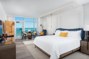a bedroom with a large white bed and a view of the ocean at The Ritz-Carlton South Beach in Miami Beach