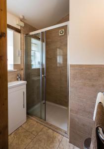 a shower with a glass door in a bathroom at Hollyhock Cottage, Clematis cottages, Stamford in Stamford