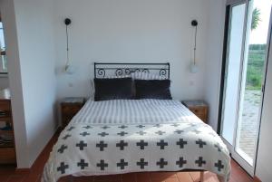 a bedroom with a bed with a black and white comforter at Monte Ramos in Ferreira do Alentejo