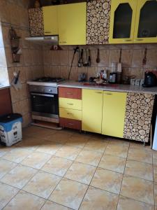 eine Küche mit gelben Schränken und Fliesenboden in der Unterkunft Casa/camere Maria in Corbu