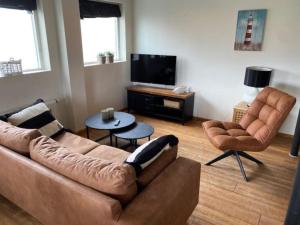 巴勒姆Ballumerhoeve Fleuri lodge的客厅里有一张沙发、两把椅子和一台电视