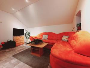 a living room with a red couch and a table at Gemütliches Apartment am Gottesberg in Muldenhammer