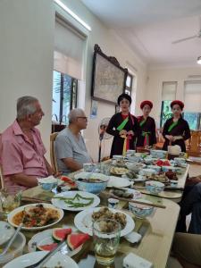 un grupo de personas sentadas alrededor de una mesa con comida en Quanho Villa, en Bắc Ninh