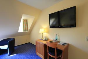 a hotel room with a desk and a flat screen tv at Residenzia Hotel Grenadier in Munster im Heidekreis