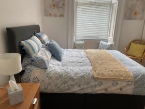 a bedroom with a bed with blue pillows and a window at Lovely main door 2 bed apartment in Edinburgh