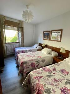 a hotel room with three beds and a chandelier at Hotel La Bilbaina de Vegadeo in Vegadeo
