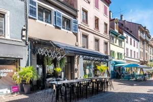 una calle con mesas y sillas en una calle con edificios en Le Georges Cuvier, en Montbéliard