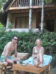 un homme et une femme assis sur une table de pique-nique dans l'établissement Riverston Du Eco Cottage, à Rattota