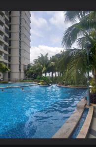 a large swimming pool with palm trees and a building at Royal Strand Danga Bay Abang Payung in Johor Bahru