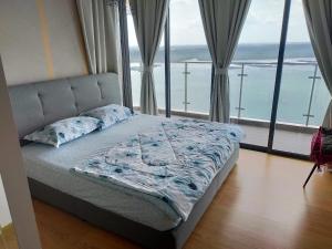 a bedroom with a bed with a view of the ocean at Royal Strand Danga Bay Abang Payung in Johor Bahru