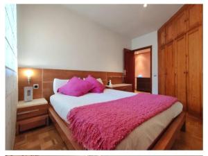1 dormitorio con 1 cama grande con almohadas rosas en Apartamento La Rocha, con garaje cerca del centro, Pamplona en Pamplona