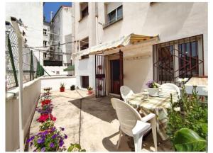 patio ze stołem, białymi krzesłami i kwiatami w obiekcie Apartamento La Rocha, con garaje cerca del centro, Pamplona w Pampelunie