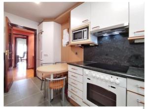 cocina con armarios blancos, mesa y microondas en Apartamento La Rocha, con garaje cerca del centro, Pamplona, en Pamplona
