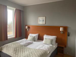 um quarto com uma cama com lençóis brancos e almofadas em Horten Budget Hotel em Horten
