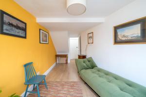 a living room with a green couch and a blue chair at ALTIDO Eclectic flat with Garden in London