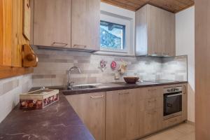 a kitchen with wooden cabinets and a sink at DolomiApartments - Casa Lagorai in Predazzo
