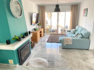 a living room with a blue couch and a tv at Modern Townhouse 5 mins walk from the beach and 15 mins from port in Manilva