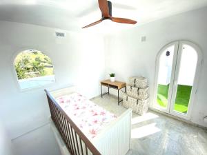 Habitación blanca con cama y ventilador de techo. en Modern Townhouse 5 mins walk from the beach and 15 mins from port en Manilva