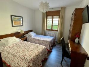 a hotel room with two beds and a desk at Hotel La Bilbaina de Vegadeo in Vegadeo +22 photos