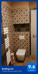 a bathroom with a toilet and a tiled wall at Blonde River Apartman Móra Szeged in Szeged