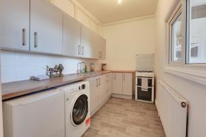 a kitchen with white cabinets and a washer and dryer at Convenient 2-Bed Apartment - Ideal for Contractors & Working Away, Free Parking, Pet Friendly, Netflix in Sheffield