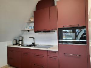 una cocina con armarios rojos y fregadero en Ferienwohnung Hafftraum, en Liepgarten