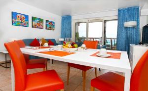 jadalnia z białym stołem i pomarańczowymi krzesłami w obiekcie Royal Islander Club Resort La Terrasse w mieście Lowlands