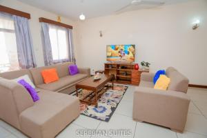 a living room with two couches and a tv at Serebian Suites in Mombasa