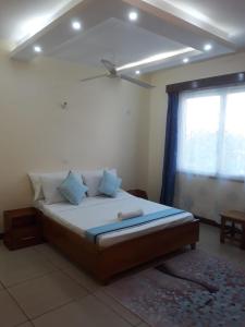 a bedroom with a bed with blue pillows and a window at Serebian Suites in Mombasa