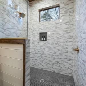 a bathroom with a shower with a stone wall at Haven Hideaway, New Luxury Cabin w/ hot tub and fire pit in Broken Bow