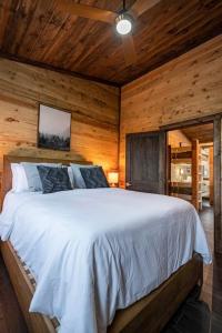 a bedroom with a white bed in a wooden room at Luxury Cabin Getaway! Hot tub, Pet Friendly, Foosball & More in Broken Bow