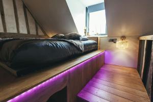Le Duplex de l'Etoile home cinéma jacuzzi et sauna privatif في Longmesnil: غرفة نوم مع سرير مع أضواء أرجوانية عليه