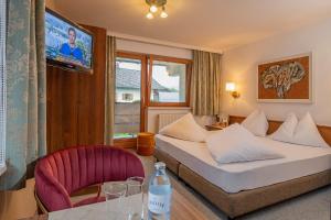 ein Hotelzimmer mit einem Bett und einem Stuhl in der Unterkunft Hotel Maximilian in Reutte