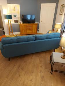 a blue couch sitting in a living room at Black Cat Cottage in Moffat