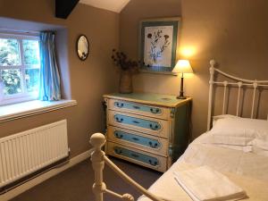 a bedroom with a bed and a dresser and a window at Bittles Cottage in Dorchester
