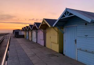 una fila di capanne da spiaggia su un molo al tramonto di Kelvin House a Fleetwood