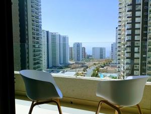two chairs sitting on a balcony with a view of a city at Apartamento cómodo y espectacular en Concón !! in Concón