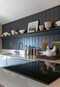 a kitchen with a sink and a counter with dishes on a shelf at Sarah's - A townhouse apartment in Georgian Holt in Holt