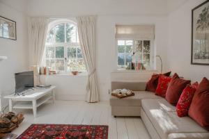sala de estar con sofá, mesa y ventanas en Butley Priory Cottage en Woodbridge