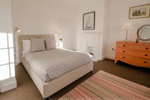 a white bedroom with a bed and a dresser and a dresser at Butley Priory Cottage in Woodbridge