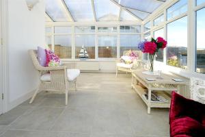 a conservatory with chairs and a table and flowers in a room at Marie-Lyn in Penrhyn Bay