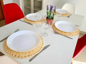 einen Tisch mit weißen Tellern und Weingläsern darauf in der Unterkunft Appartement El Campello plage in El Campello