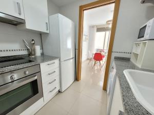 eine weiße Küche mit einem Herd und einem Kühlschrank in der Unterkunft Appartement El Campello plage in El Campello