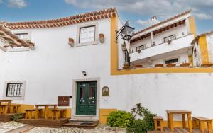 a white building with a green door and tables at Casa de S. Thiago de Obidos in Óbidos