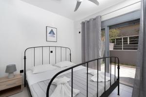 a bedroom with a black bed and a window at Luna Apartment by A&D Properties in Porto Rafti