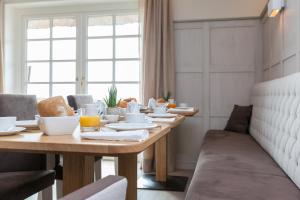 a dining room with a wooden table with food on it at Hotel Watthof in Rantum